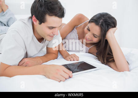 Couple using a tablet lying in bed in the bedroom Stock Photo