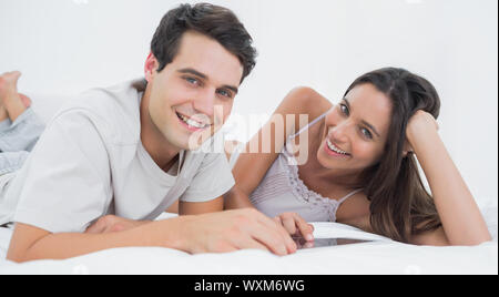 Portrait of a couple using a tablet lying in bed in the bedroom Stock Photo
