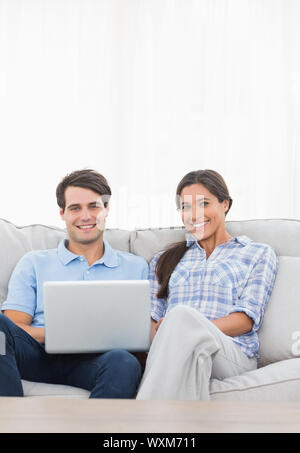 Portrait of a couple relaxing with a laptop sat on a couch Stock Photo