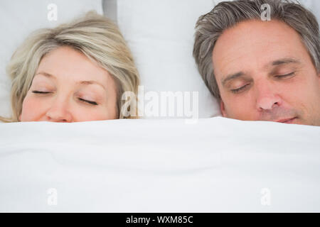Couple sleeping under the covers at home in bed Stock Photo