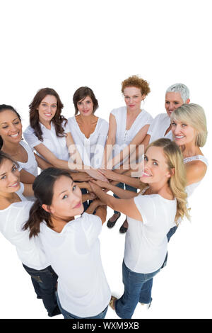 Happy female models joining hands in a circle and looking at camera on white background Stock Photo