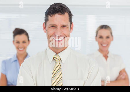 Smiling businessman posing  in bright office with his colleagues on background Stock Photo