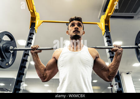 Man at the gym. Execute exercise squatting with weight, in gym Stock Photo