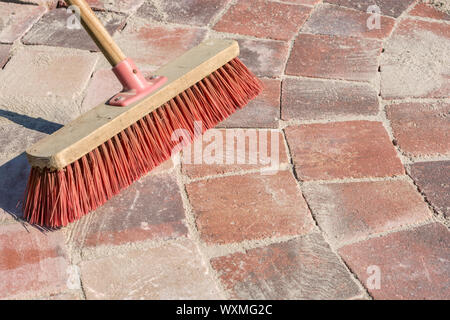 Paved walkway is grouted with fine-grained sand and a broom Stock Photo