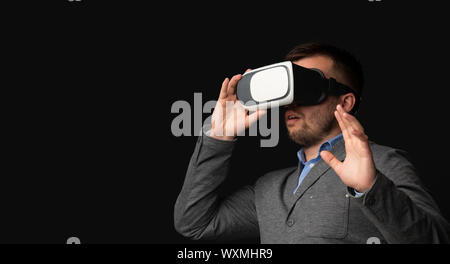 Shocked businessman wearing VR headset, touching virtual object Stock Photo