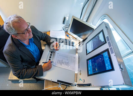 17 September 2019, Saxony, Schlettau: Thomas Kayser, a railcar driver from the military and transport company Thales, controls a railcar during a test drive at Schlettau station using a mobile suitcase with cockpit and route information. The train is remotely controlled by him via the new 5G mobile radio standard. Vodafone has built one of the first 5G stations in Germany at the station in Schlettau. In the future, trains could be controlled remotely, for example in freight transport. The research train is part of the Smart Rail Connectivity Campus project led by Chemnitz University of Technol Stock Photo