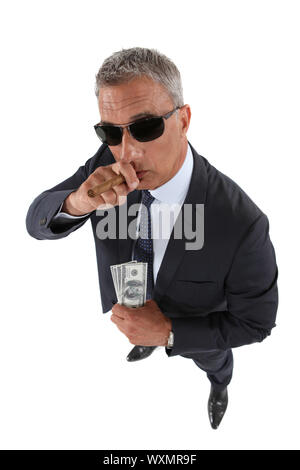 A crook holding stolen money and smoking a cigar Stock Photo