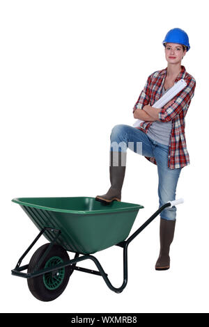 Tradeswoman with her foot propped on a wheelbarrow Stock Photo