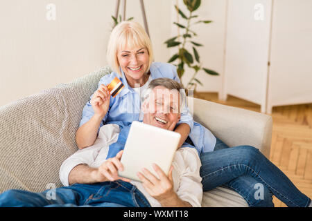 Modern elderly couple shopping online with tablet and credit card Stock Photo