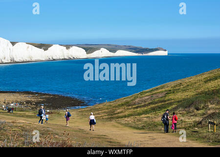 Walkers on the South Downs at Seaford Head, near Eastbourne, East Sussex, looking east towards Seven Sisters cliffs Stock Photo