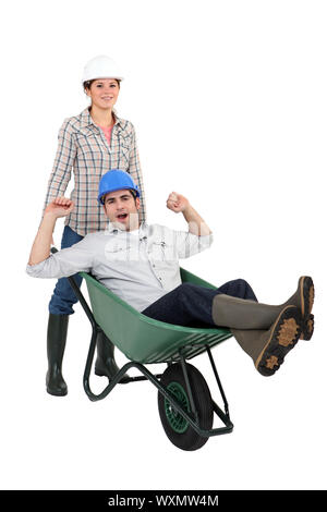 Woman pushing her colleague in a wheelbarrow Stock Photo