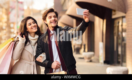 Young couple taking selfie near boutiques outdoors Stock Photo