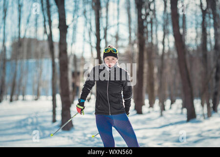 Cross-country skiing woman doing classic nordic cross country skiing in trail tracks in snow covered forest. Training track for skiers in the park of Stock Photo