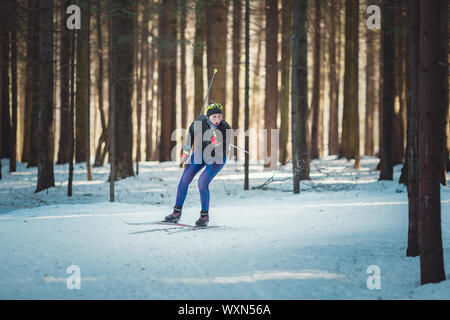 Cross-country skiing woman doing classic nordic cross country skiing in trail tracks in snow covered forest. Training track for skiers in the park of Stock Photo