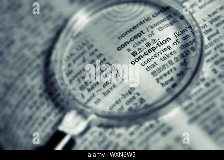 Focus on conception word with magnifier in book. Stock Photo