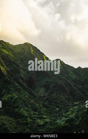 First rays of sunlight light up the beautiful and rugged green mountains of Oahu. Stock Photo