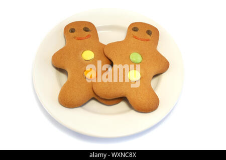 Two Gingerbread men on a cream plate on a white background Stock Photo