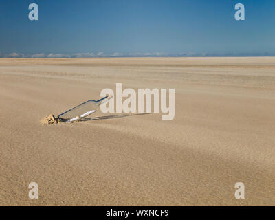 A bottle with a message inside is abandoned in the desert. Stock Photo