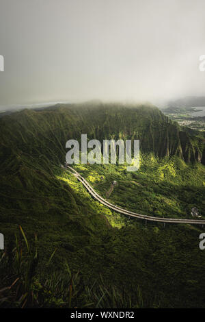 Mountain top views in Oahu. Dirt trail on ridgeline looking back down the valley towards the start of the Moanalua Valley Trail. Stock Photo