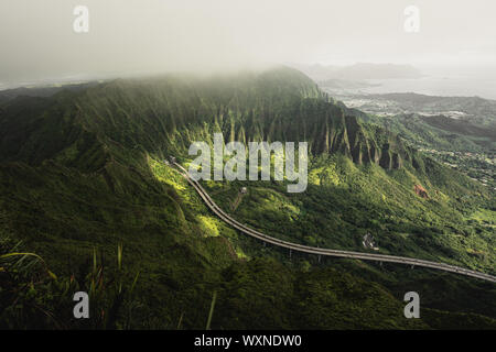 Mountain top views in Oahu. Dirt trail on ridgeline looking back down the valley towards the start of the Moanalua Valley Trail. Stock Photo