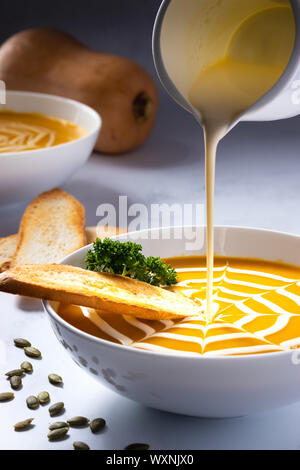 Pumpkin soup with cream pour Stock Photo