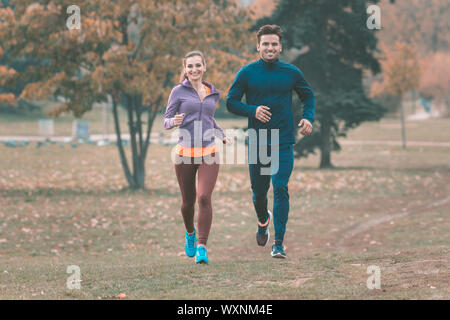 Couple in wonderful fall landscape running for better fitness towards the camera Stock Photo