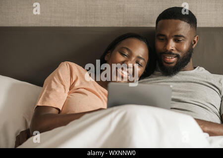 Young African American couple using a digital tablet in bed Stock Photo