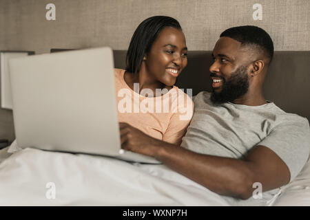Smiling African American couple using a digital tablet in bed Stock Photo