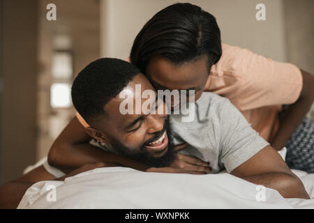 Laughing young African American couple playing in bed together Stock Photo