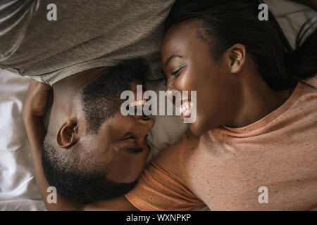 Affectionate young African American couple laughing together in bed Stock Photo