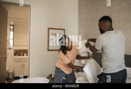 Laughing African American couple having a pillow fight in bed Stock Photo