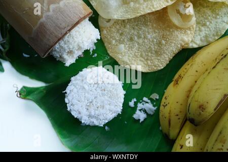 Kerala breakfast white rice puttu made in bamboo mould with Papad and banana, top view selective focus Stock Photo