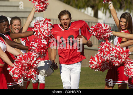 Football Player Running Through Cheerleaders Stock Photo