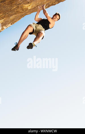 Climber Jumping off Cliff Stock Photo