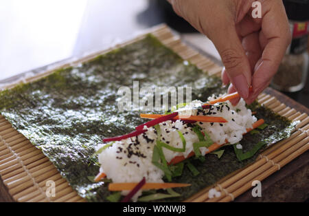 Woman using bamboo rolling mat for home made sushi Stock Photo - Alamy