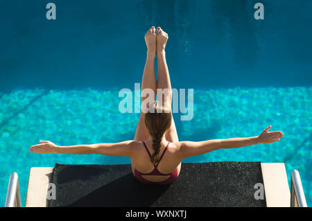 Female swimmer sitting on diving board Stock Photo