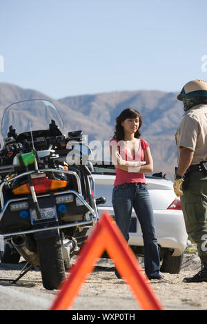 Police officer talking to driver experiencing car breakdown Stock Photo