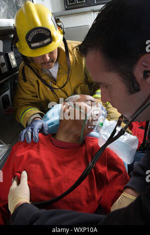 Firefighter and paramedic helping man in ambulance Stock Photo