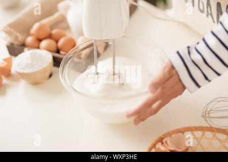 Mixing white egg cream in bowl with motor mixer, baking cake Stock Photo