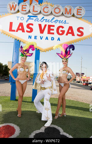 Female dancers and Elvis impersonator posing in front of Las Vegas welcome sign, Nevada, USA Stock Photo