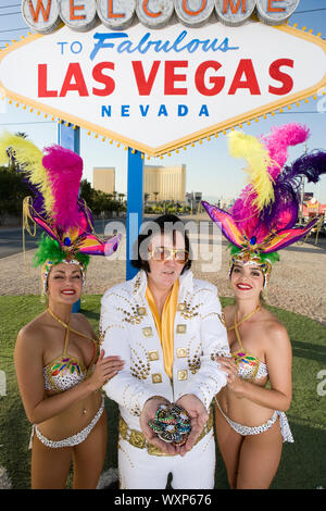 Female dancers and Elvis impersonator posing in front of Las Vegas welcome sign, Nevada, USA Stock Photo