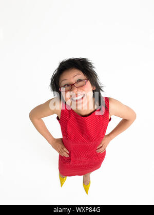 Elevated view of a happy woman in red dress with hands on hips against white background Stock Photo