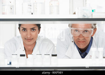 Two multiethnic scientists looking through shelves in laboratory Stock Photo