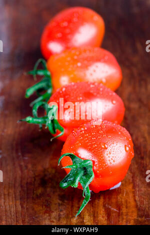 macro images of four wet tomatoes closeup on wooden table Stock Photo