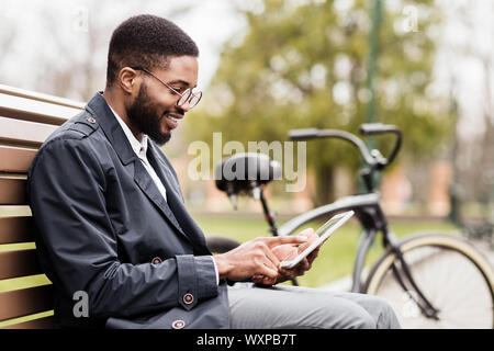 Freelance work. Young man using digital tablet in park Stock Photo
