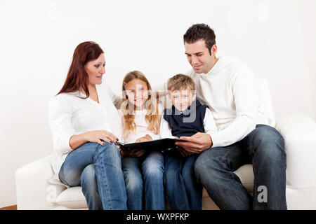 Hapy young family watching photo album at home Stock Photo