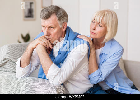 Senior woman consoling husband after arguing at home Stock Photo