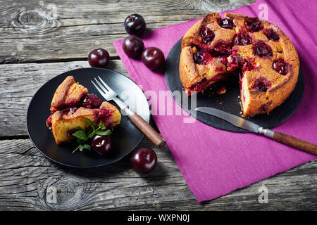 delicious sliced plum torte on a black plate on a rustic wooden table, horizontal view from above, close-up Stock Photo