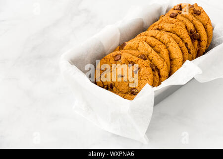 Homemade chocolate chip cookies in a baking form on white marble background with copy space. Angled view. Stock Photo