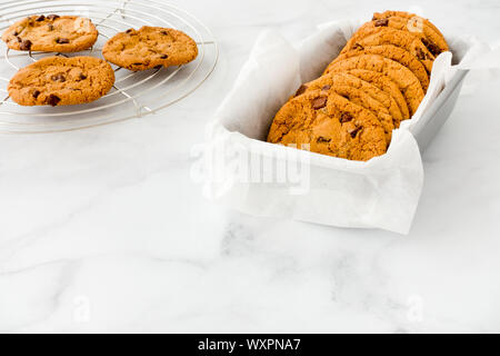Closeup of homemade chocolate chip cookies in a baking form and on a cooling rack. Stock Photo